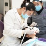 Two dentists performing a dental procedure on a patient in a modern clinic setting.