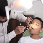 A dentist checks a child's teeth in a well-lit dental clinic, focusing on oral care.