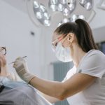 Female dentist working on a patient in a modern dental office with bright lighting.